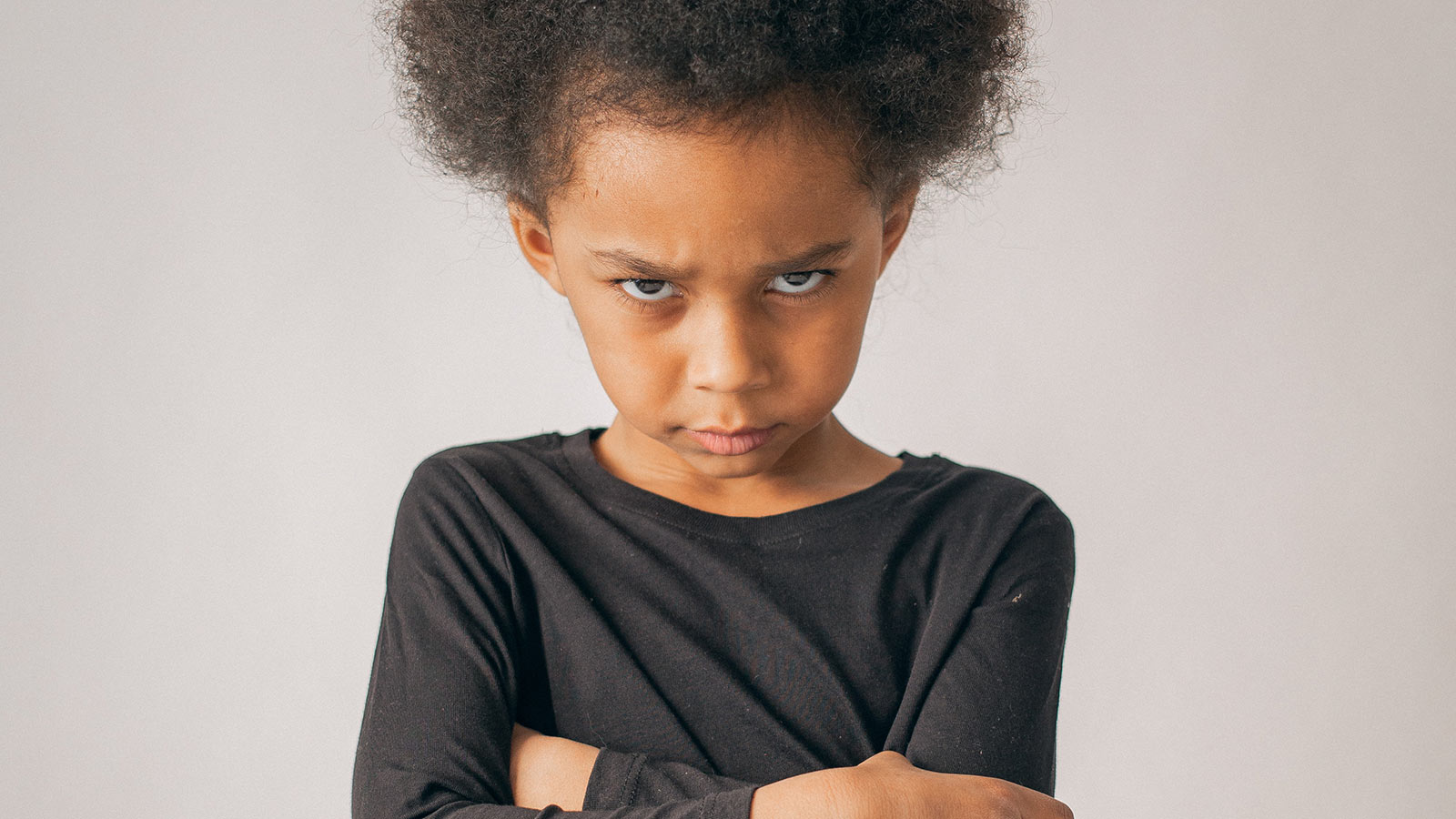 angry child folding arms and looking at camera, reframing behavior