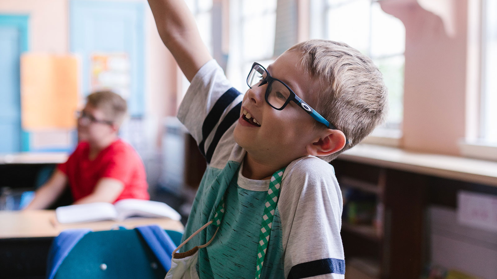 little boy raising his hand in school