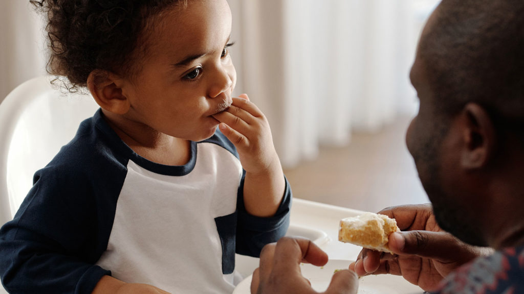 father feeding his son a piece of bread