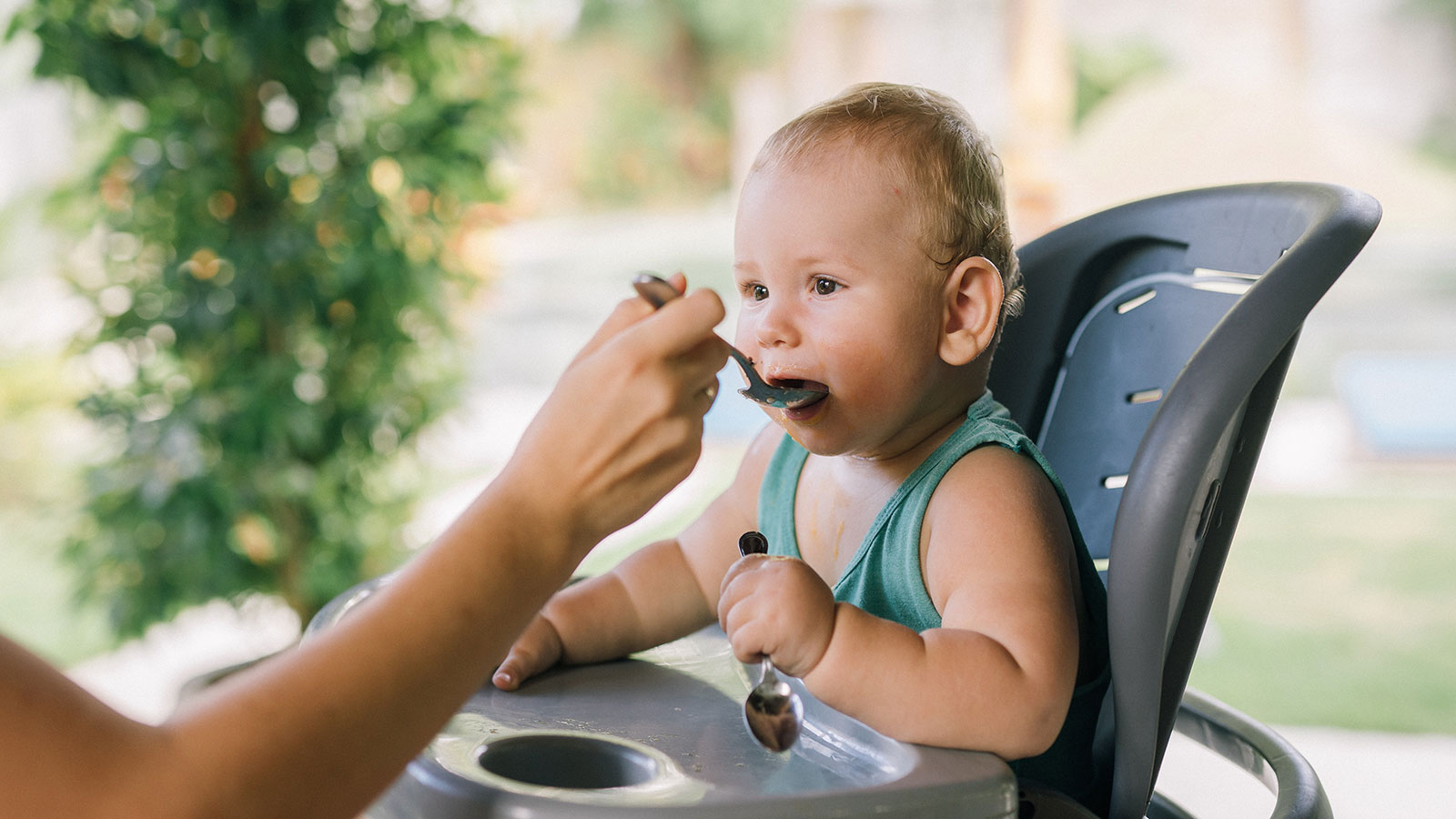 parent spoon feeding their baby in a high chair
