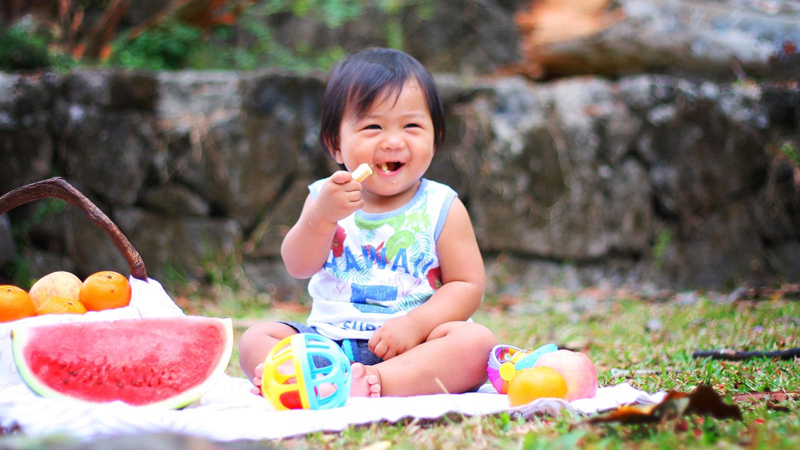 Asian baby eating and playing on a picnic blanket