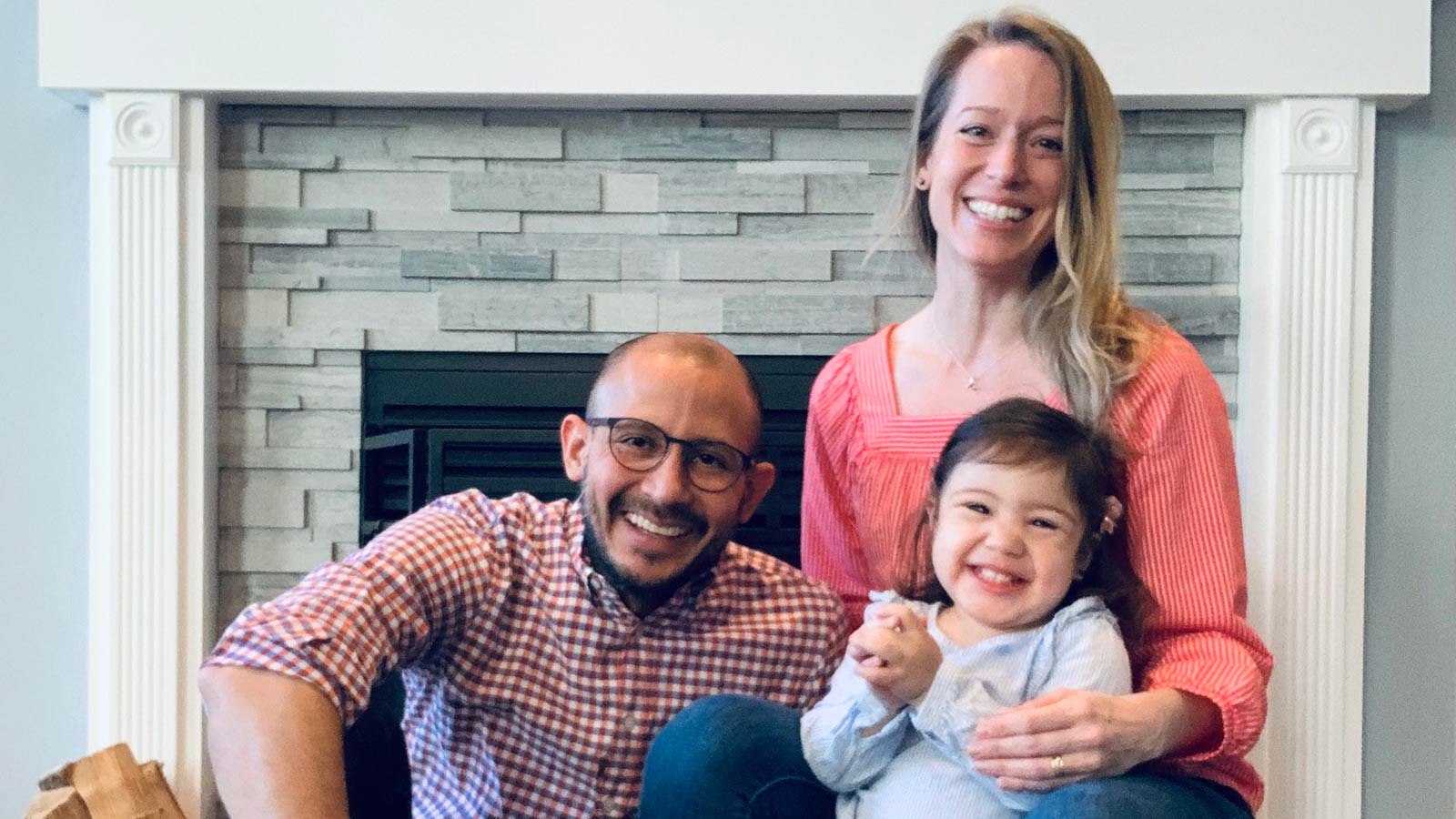 parents with daughter in front of fireplace