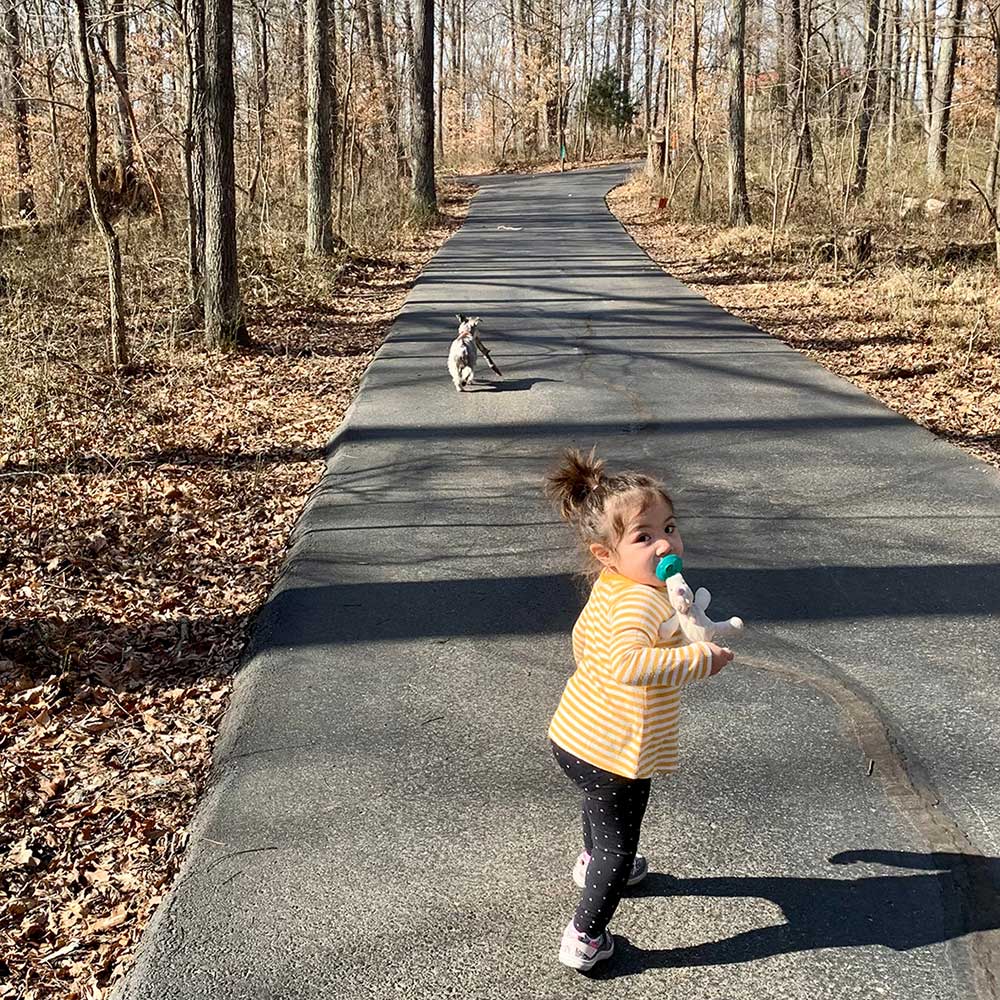 little girl with pacifier walking with her dog