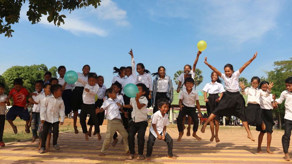 group of children holding balloons and jumping into the air