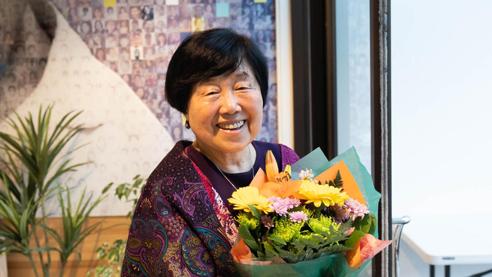 a smiling Nancy Kim holding bouquets of flowers