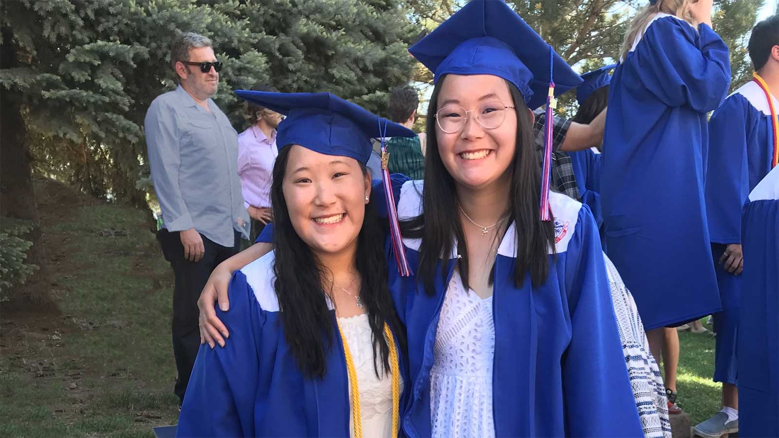 adopted sisters on graduation day with arms around each other