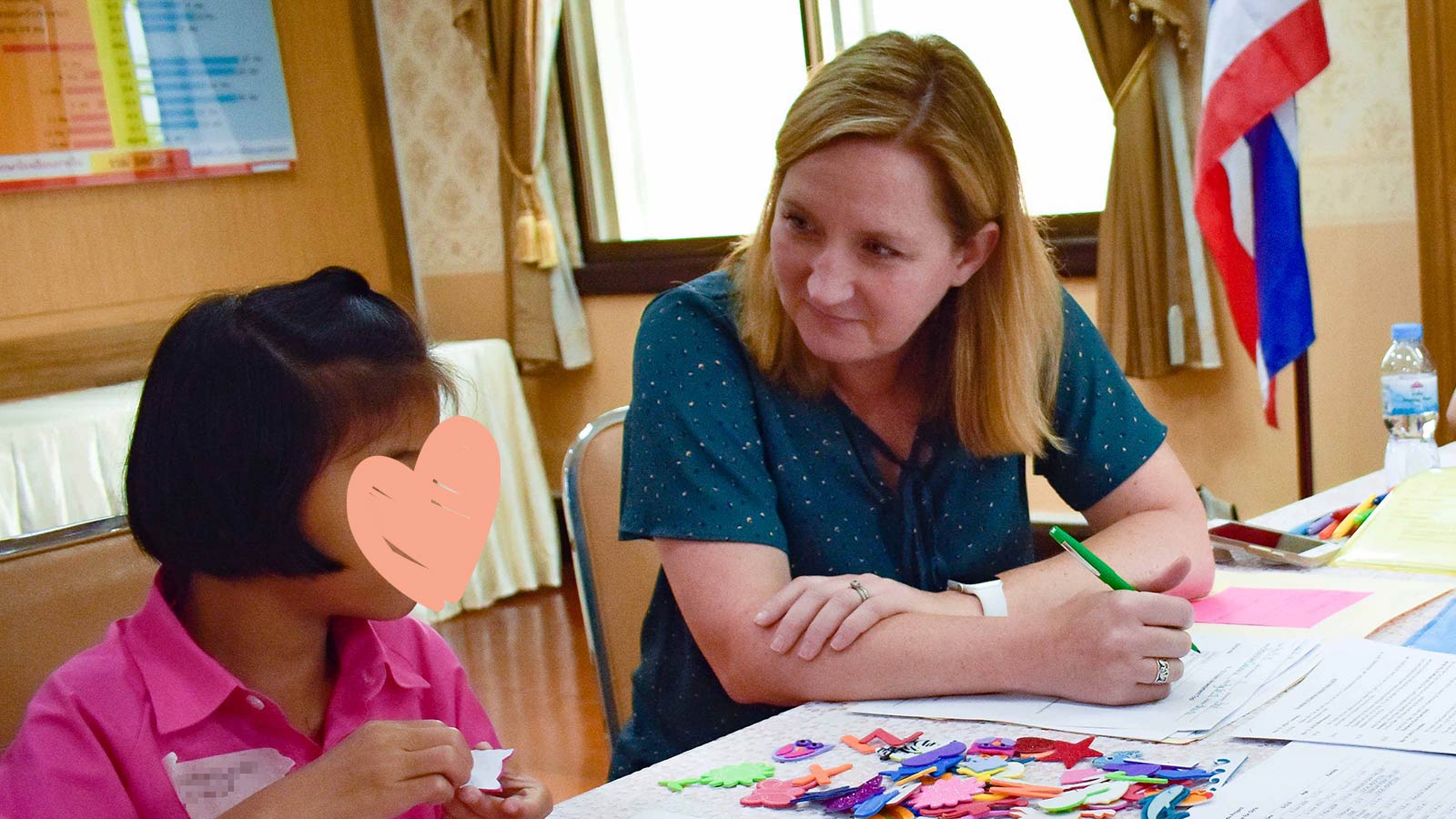 smiling poppy who needs an adoptive family with Holt staff making crafts