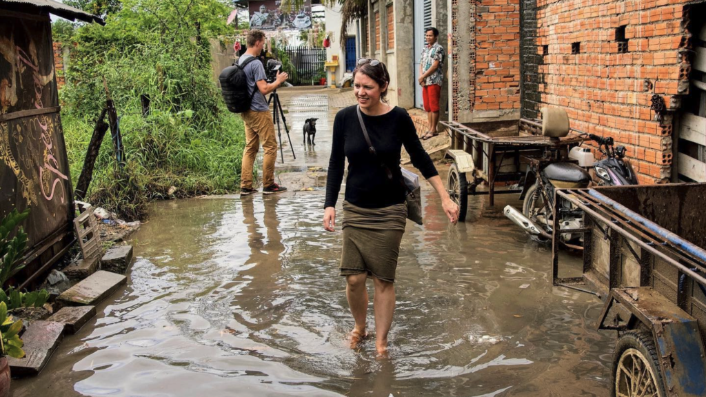 Robin wades through ankle-deep water on a street in Cambodia