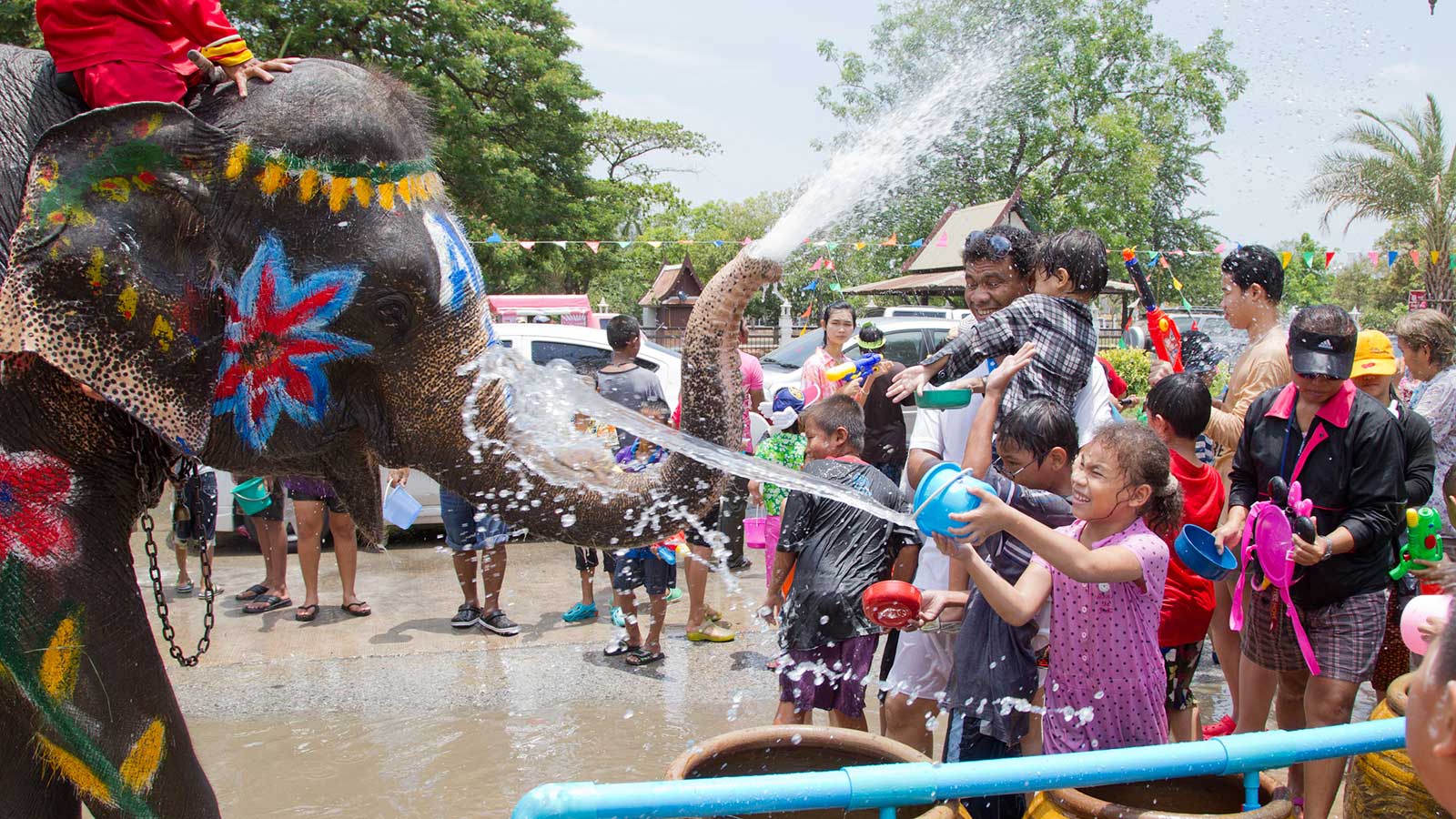 little girl spraying water at decorated elephant for songkran in thailand