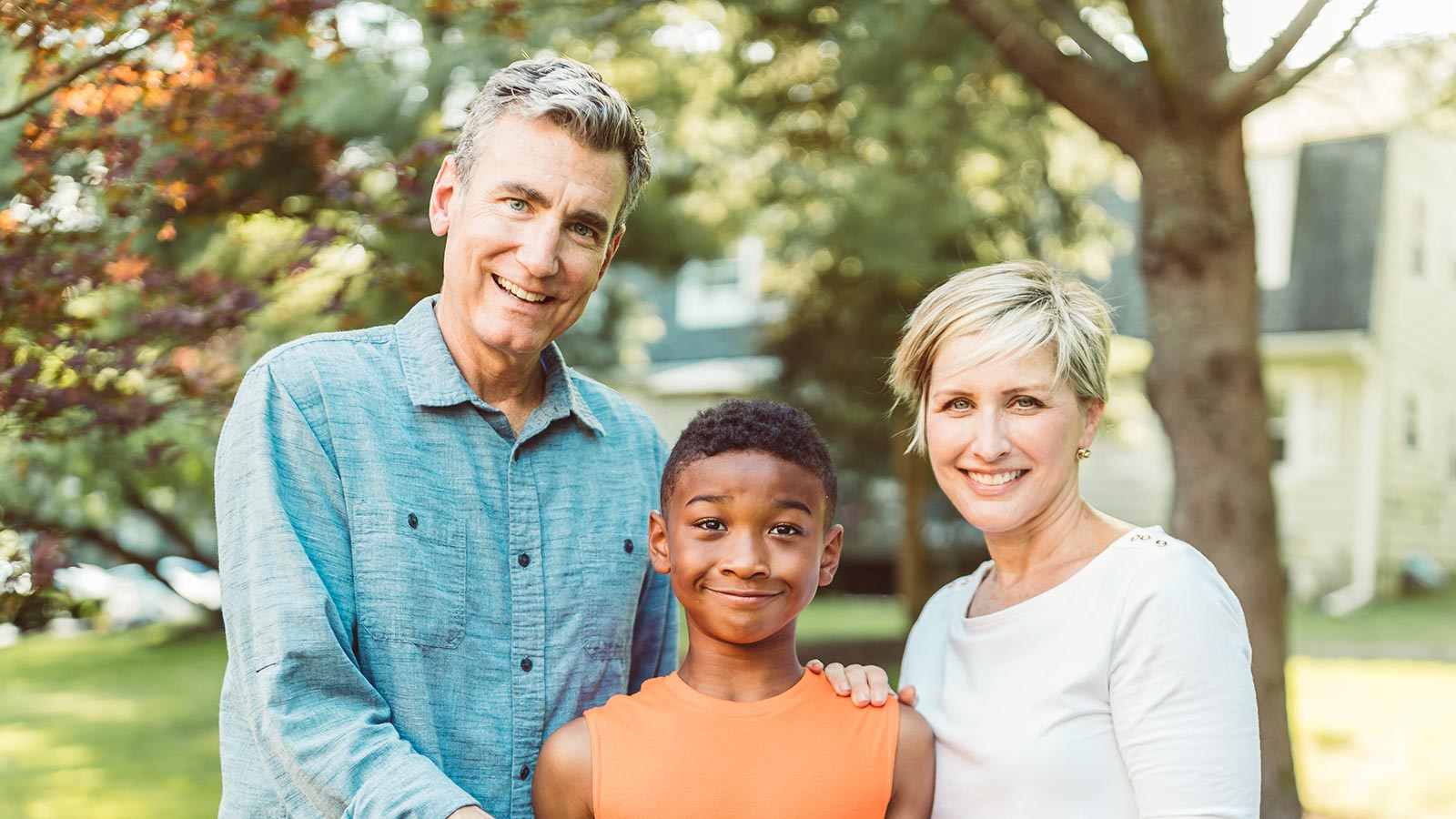 smiling adoptive parents with arms around adopted son