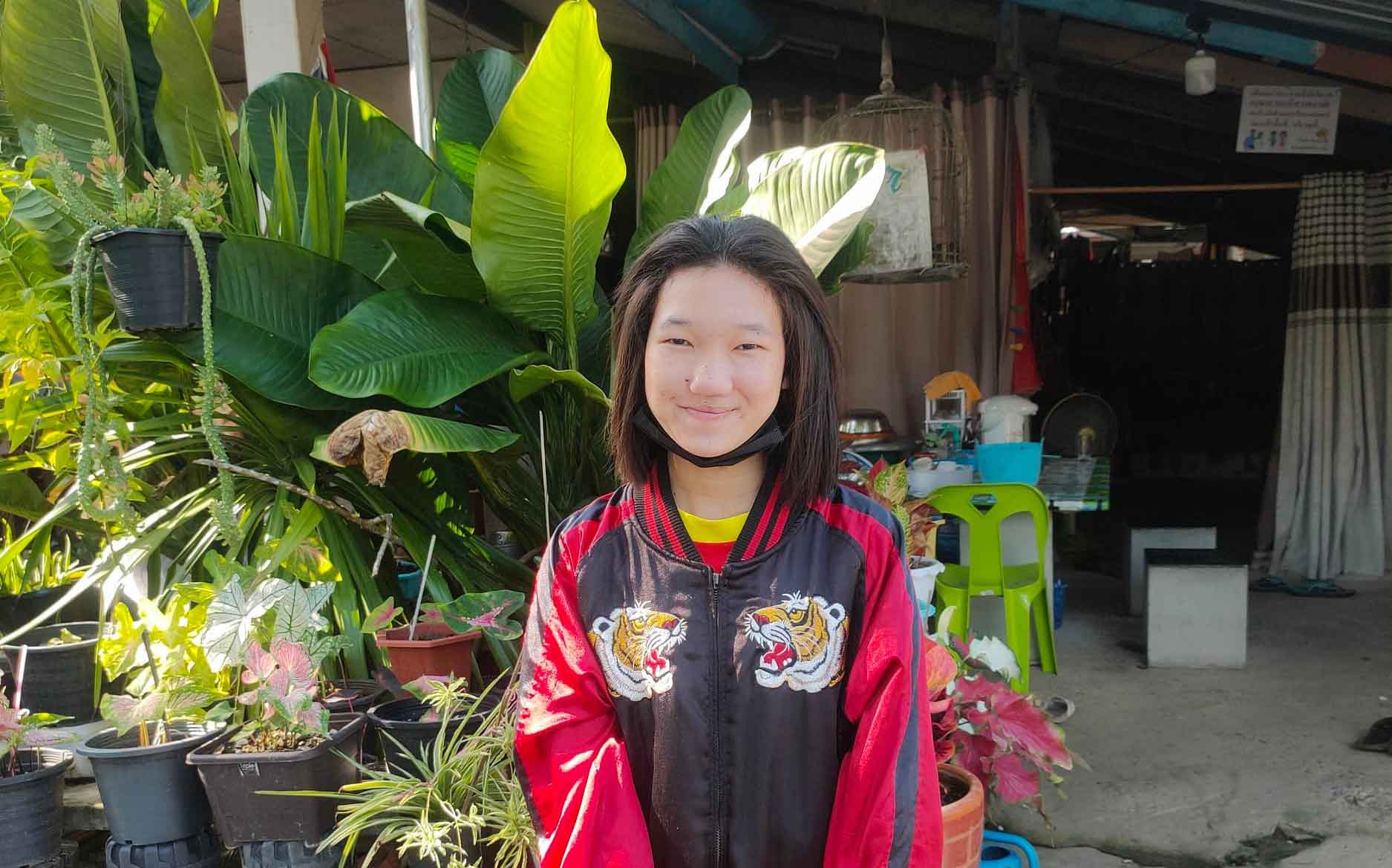 Teenage girl receiving Holt support in Thailand standing in front of her garden