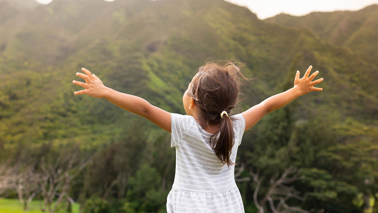 hopeful little girl in child sponsorship program lifting hands into the air