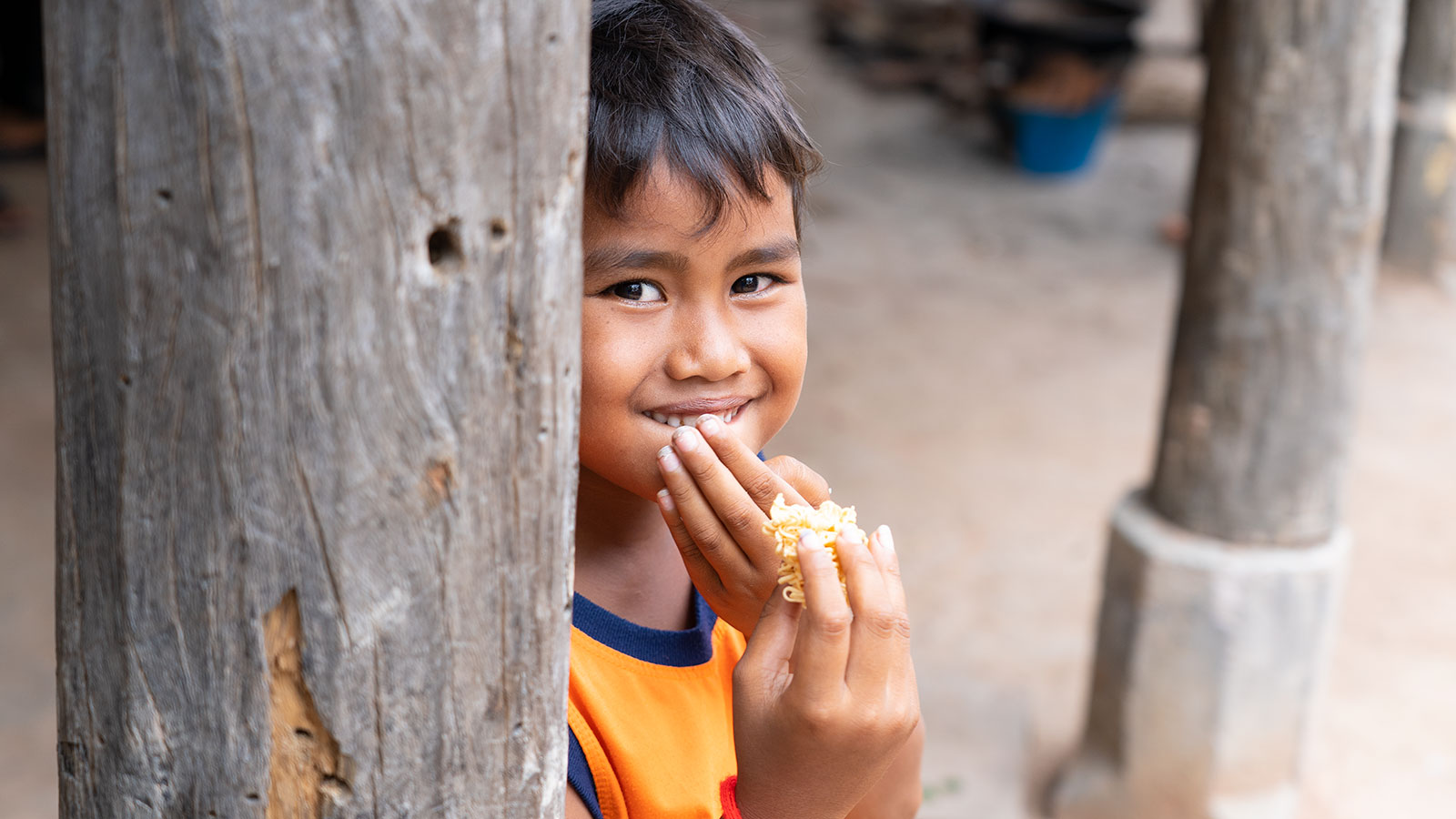 boy in Holt's programs in Cambodia eating dry ramen noodles