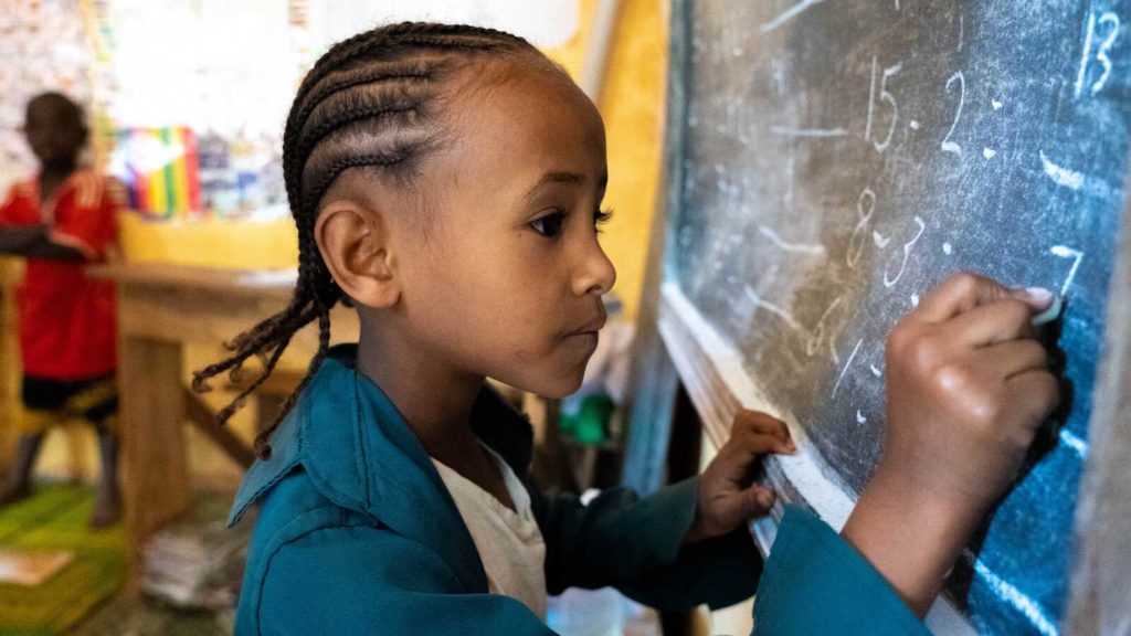 A girl solves math problems on a chalk board at an early childhood development center in Ethiopia.