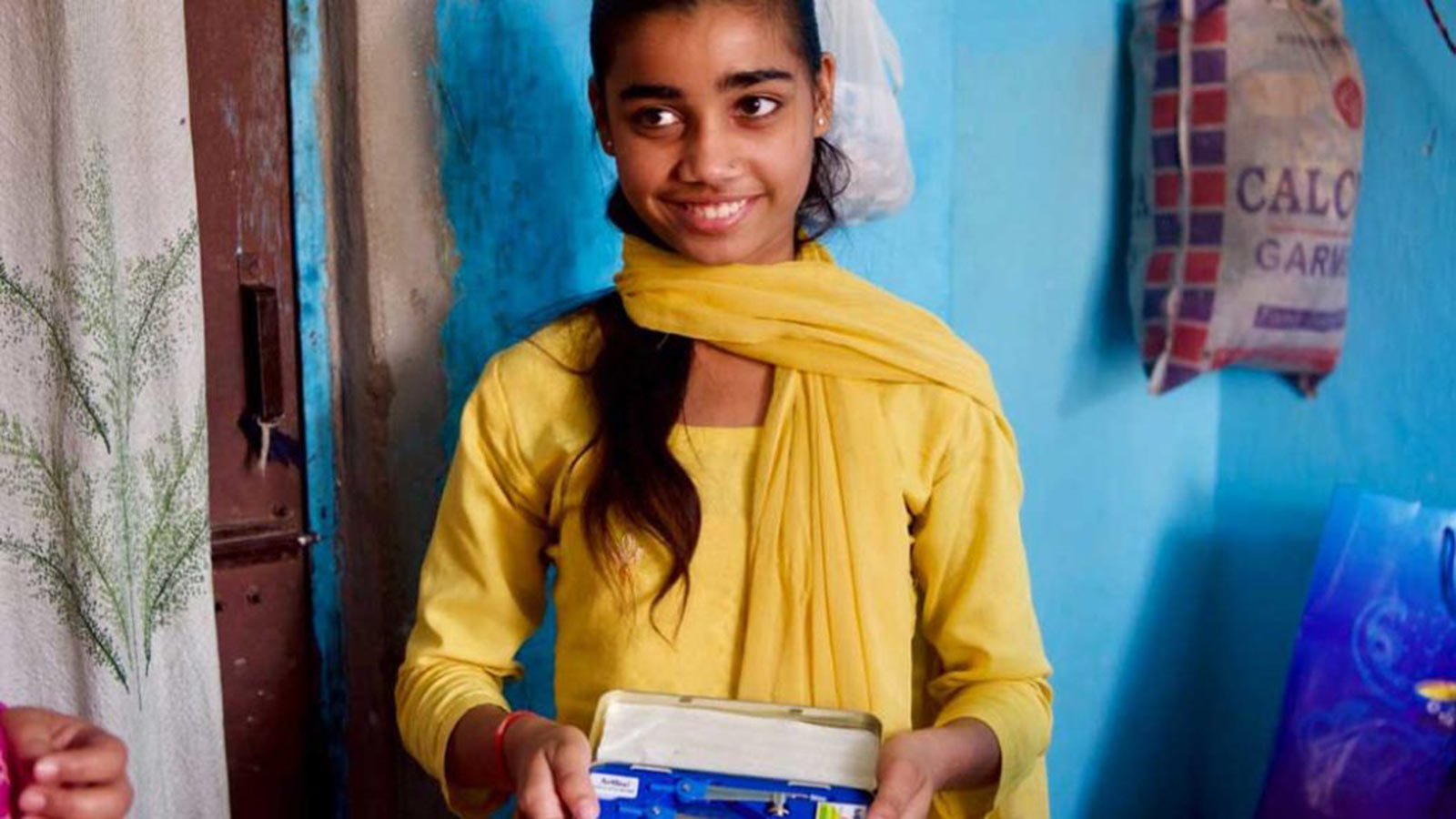Smiing girl in yellow sari who received educational support