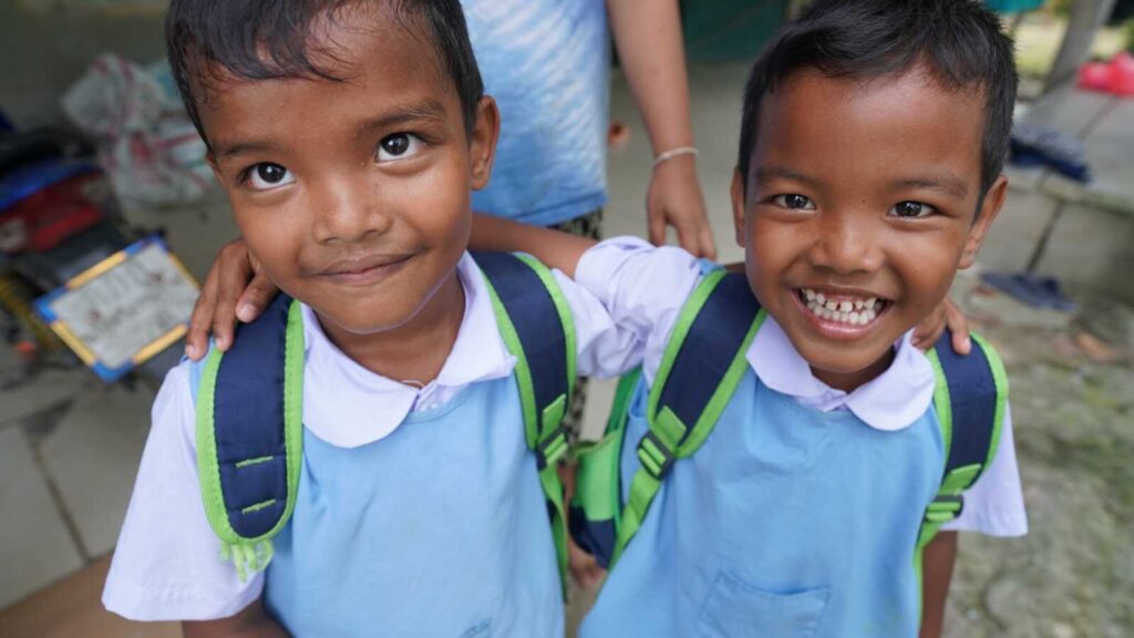 Sponsored twins hugging in school uniforms in Thailand