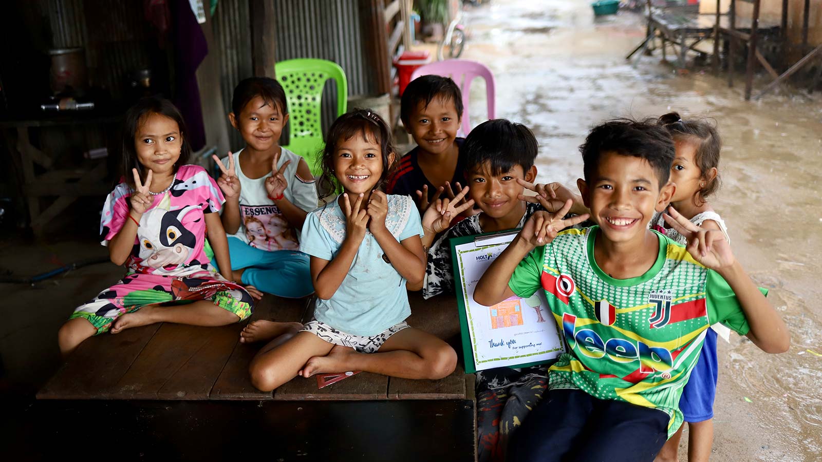 a day in the life of a holt cambodia social worker visiting a group of children smiling for the camera