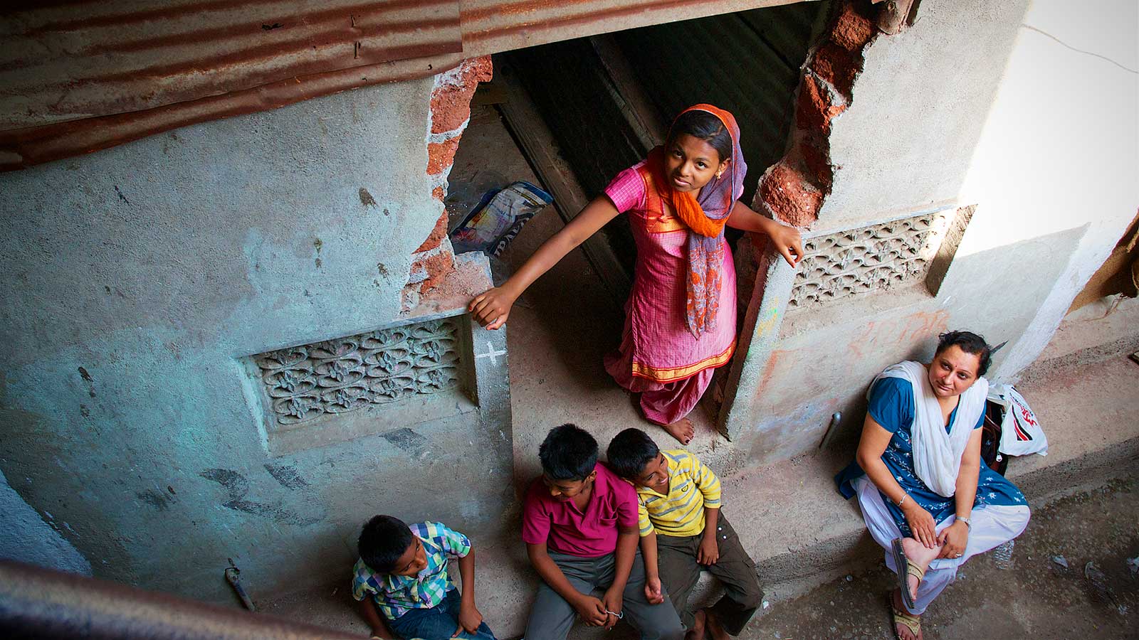 girl standing in the doorway of a home in india looking up at the camera