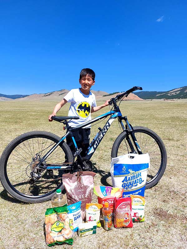 child sponsor, little boy in Mongolia with bike, food and other supplies in front of him