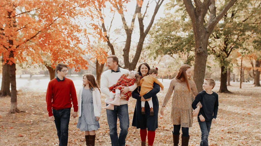 A large adoptive family walks in the fall leaves
