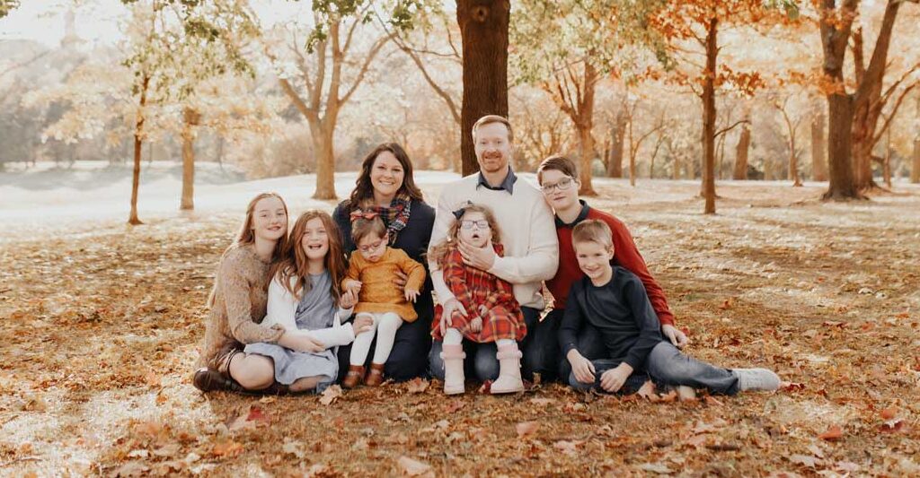 A large adoptive family photo in the fall leaves