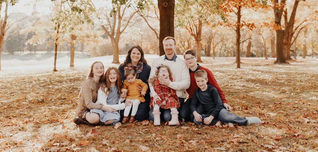 A large adoptive family photo in the fall leaves