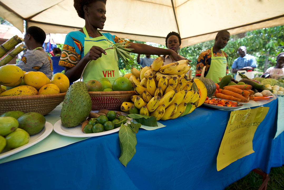 A health worker points to vegetables piled on a table