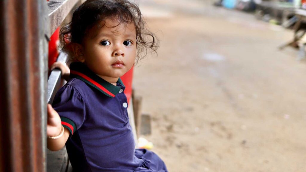 a young girl sits on a bench and looks at the camera