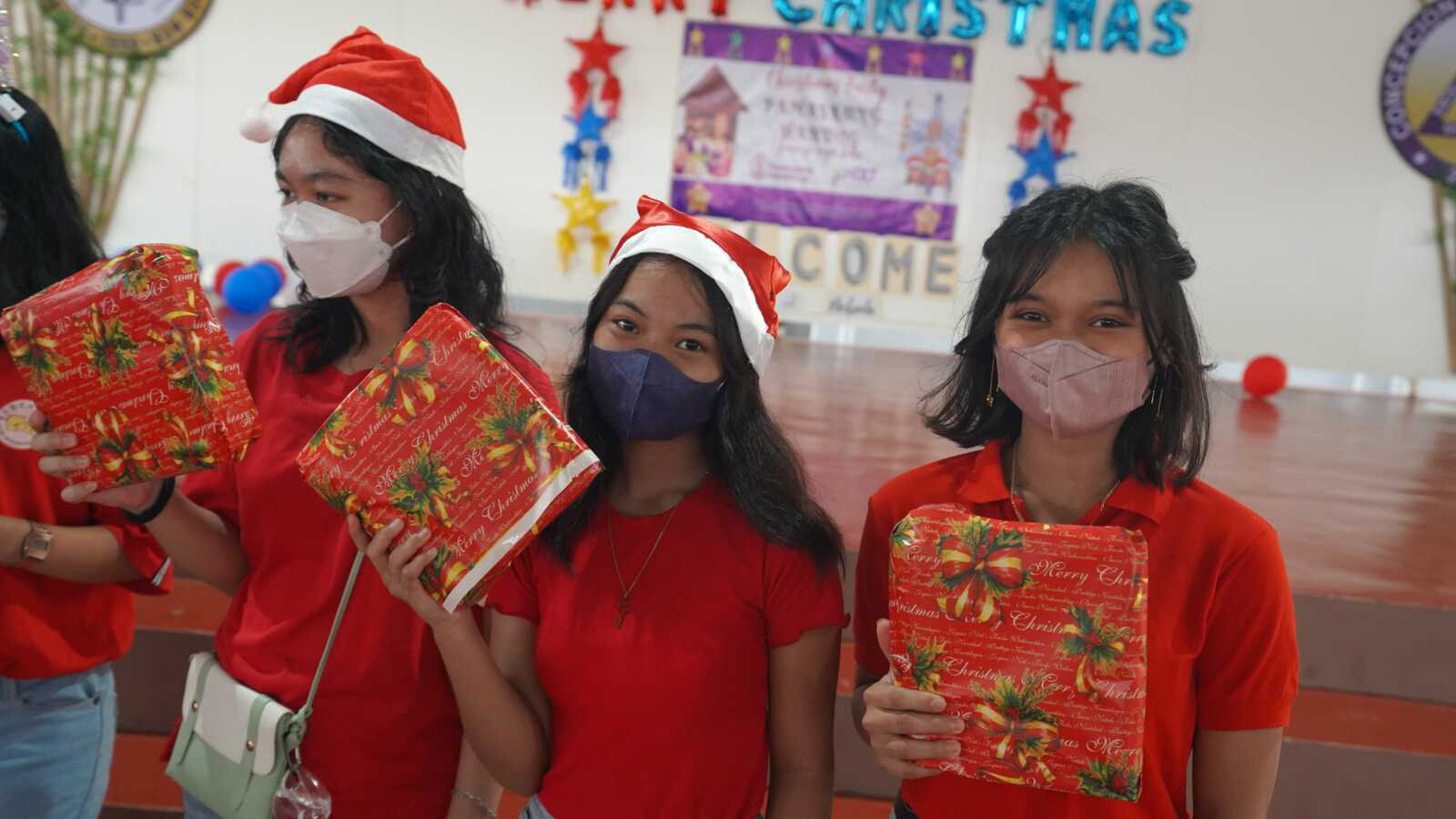 Sponsored students hold the presents they received at a Christmas party in the Philippines