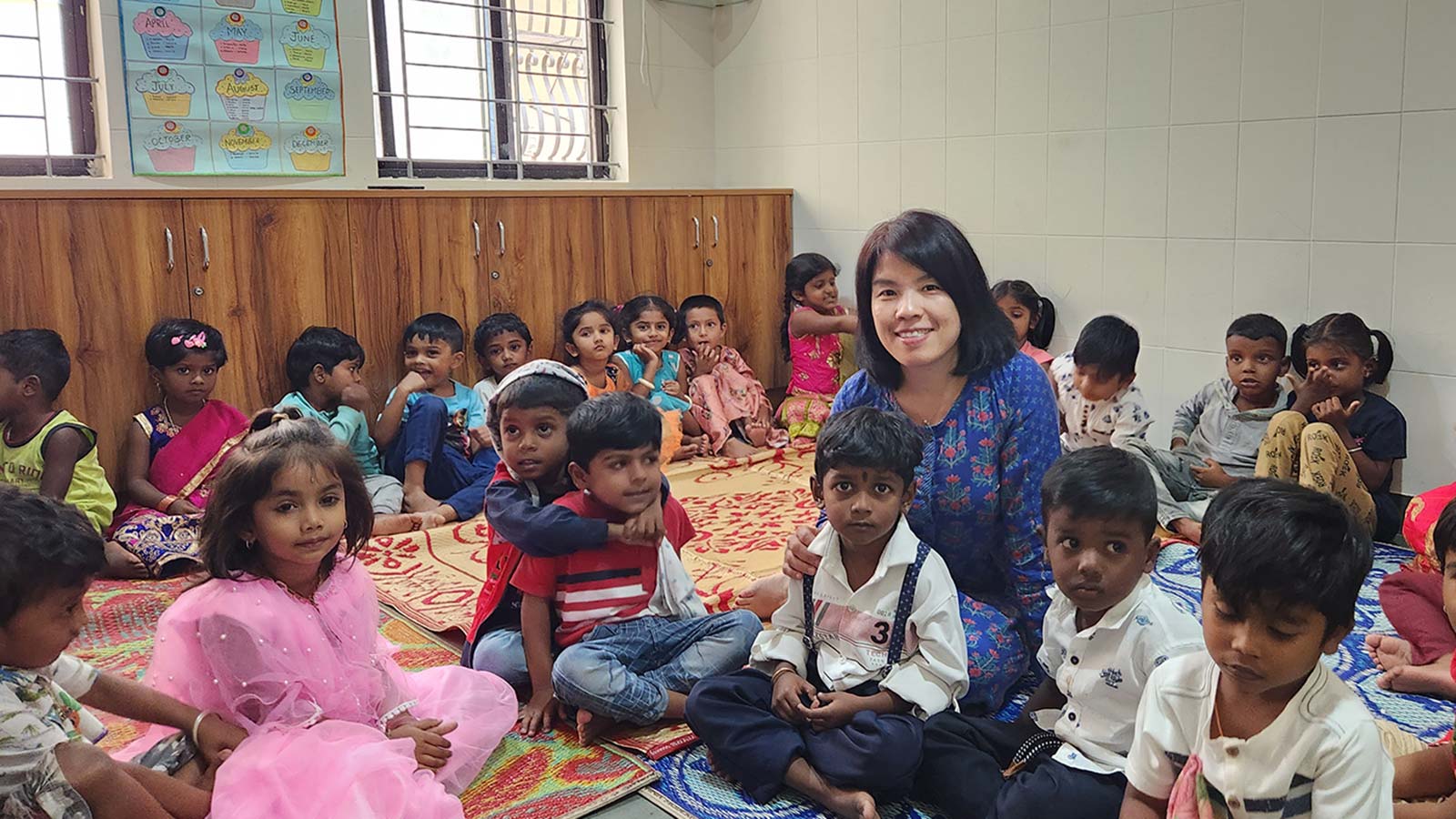 Holt VP Thoa Bui sitting on the floor with children in migrant daycare in India