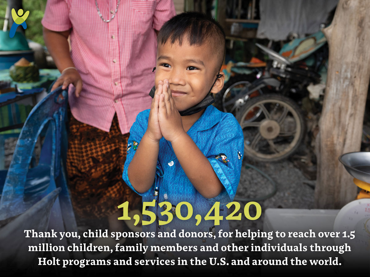 A boy holds his hands in prayer pose to say thank you with a global giving in 2022 impact number.