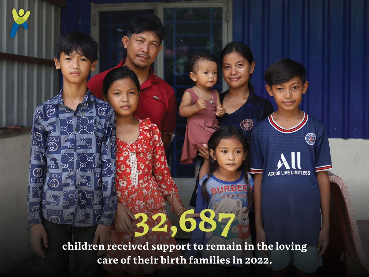 A family in Cambodia poses in front of the new house donors provided with a global giving in 2022 impact number.