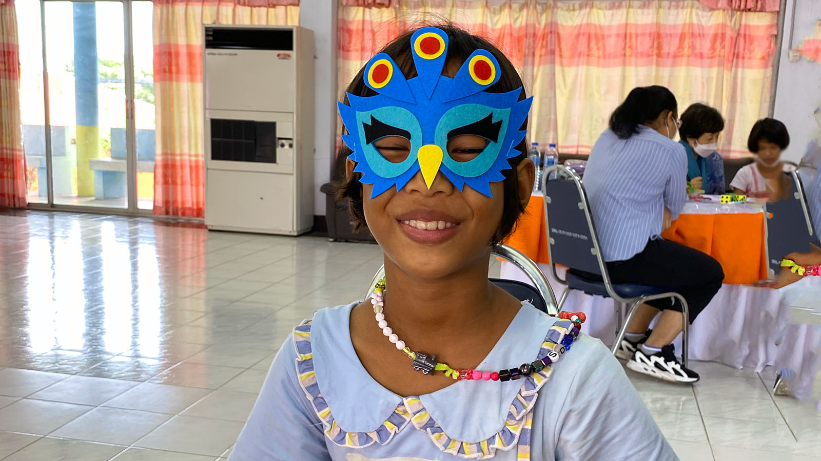 Girl smiling in blue mask bead necklace