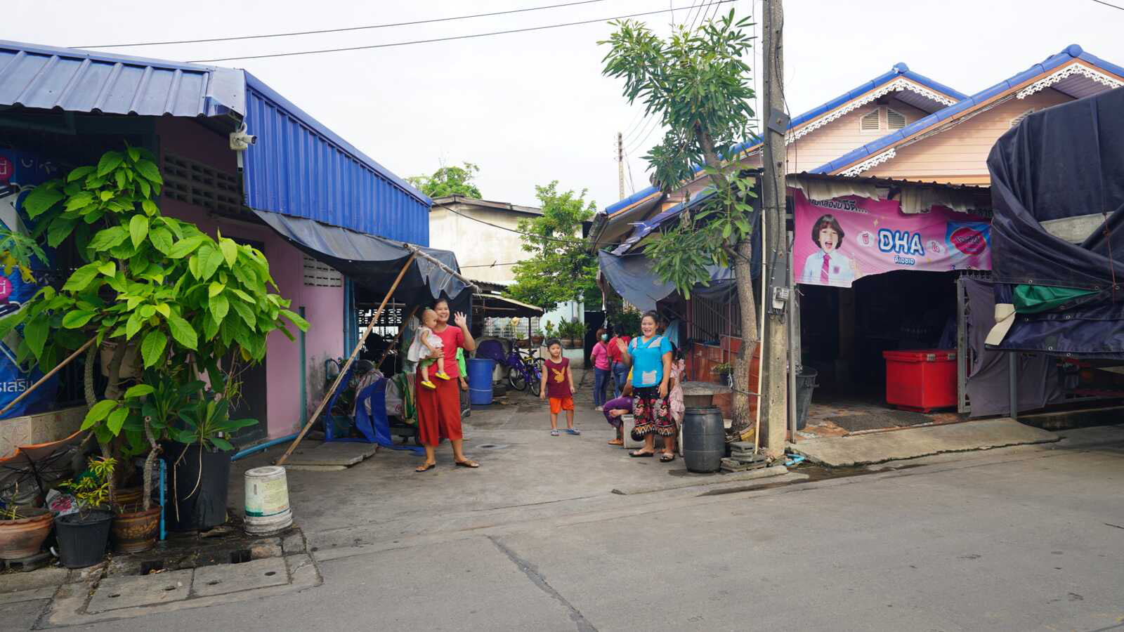Burmese migrants in Thailand wave on a street corner