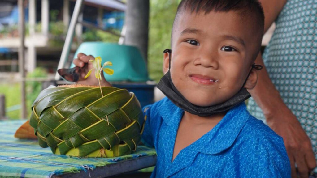 A boy in Holt sponsorship smiles as he eats coconut jelly
