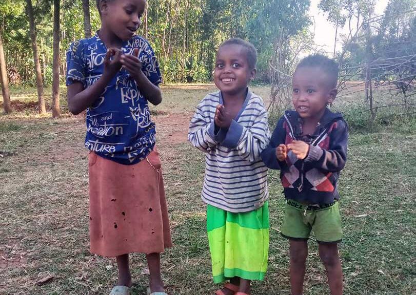 Three siblings smile outside in Ethiopia