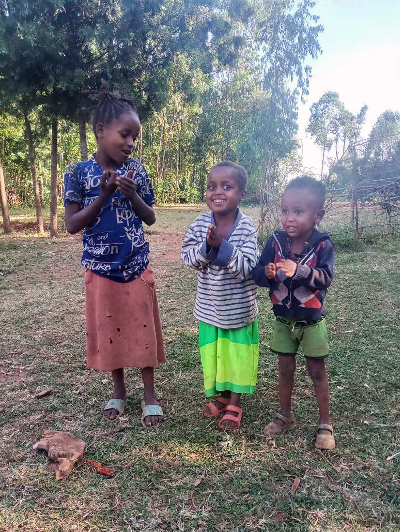 Three siblings smile outside in Ethiopia
