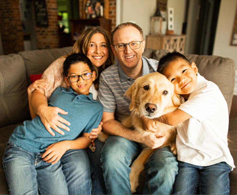 McDougal family photo at home with dog, adoption agency review of Holt after adopting two sons from Taiwan