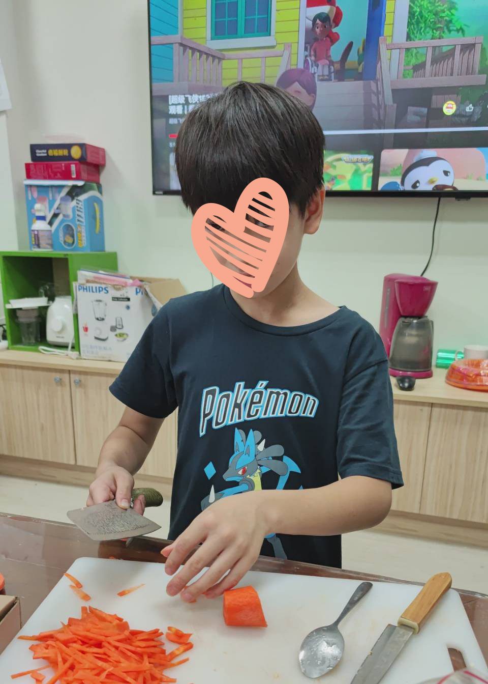 Young boy in Pokemon t-shirt chops food in the kitchen