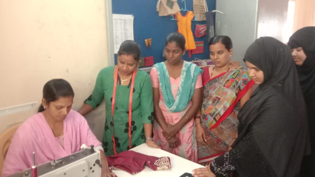 A group of women gathers around a sewing machine