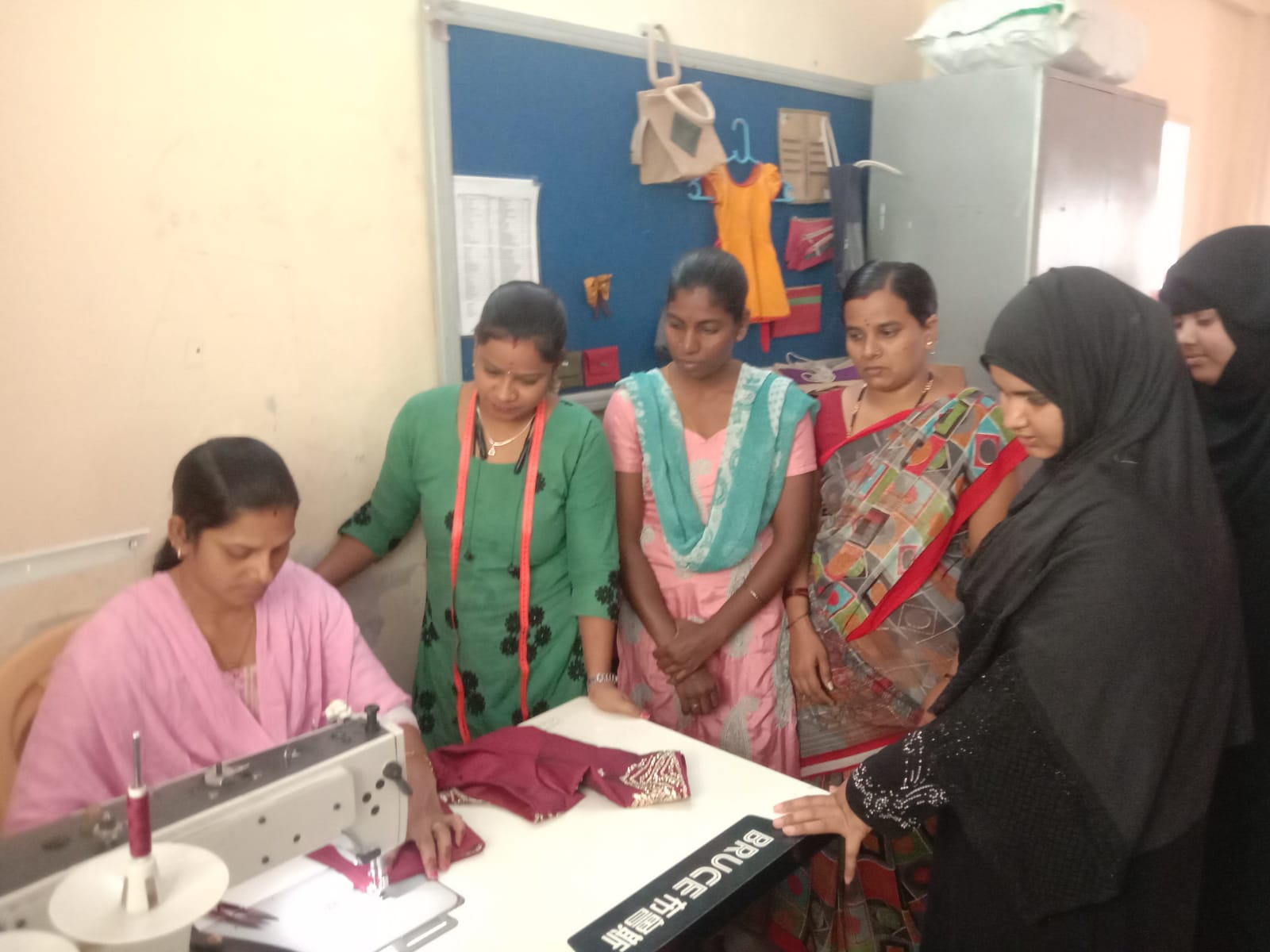 A group of women gathers around a sewing machine