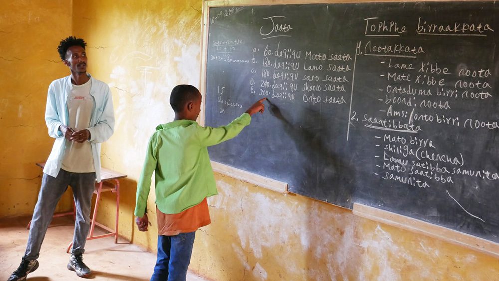 Young boy in Ethiopia works at a blackboard in a rural classroom
