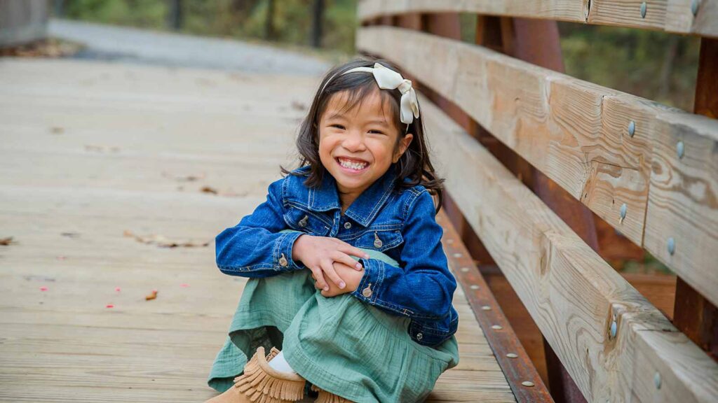 Holt International adoptee Bain smiling on wooden bridge