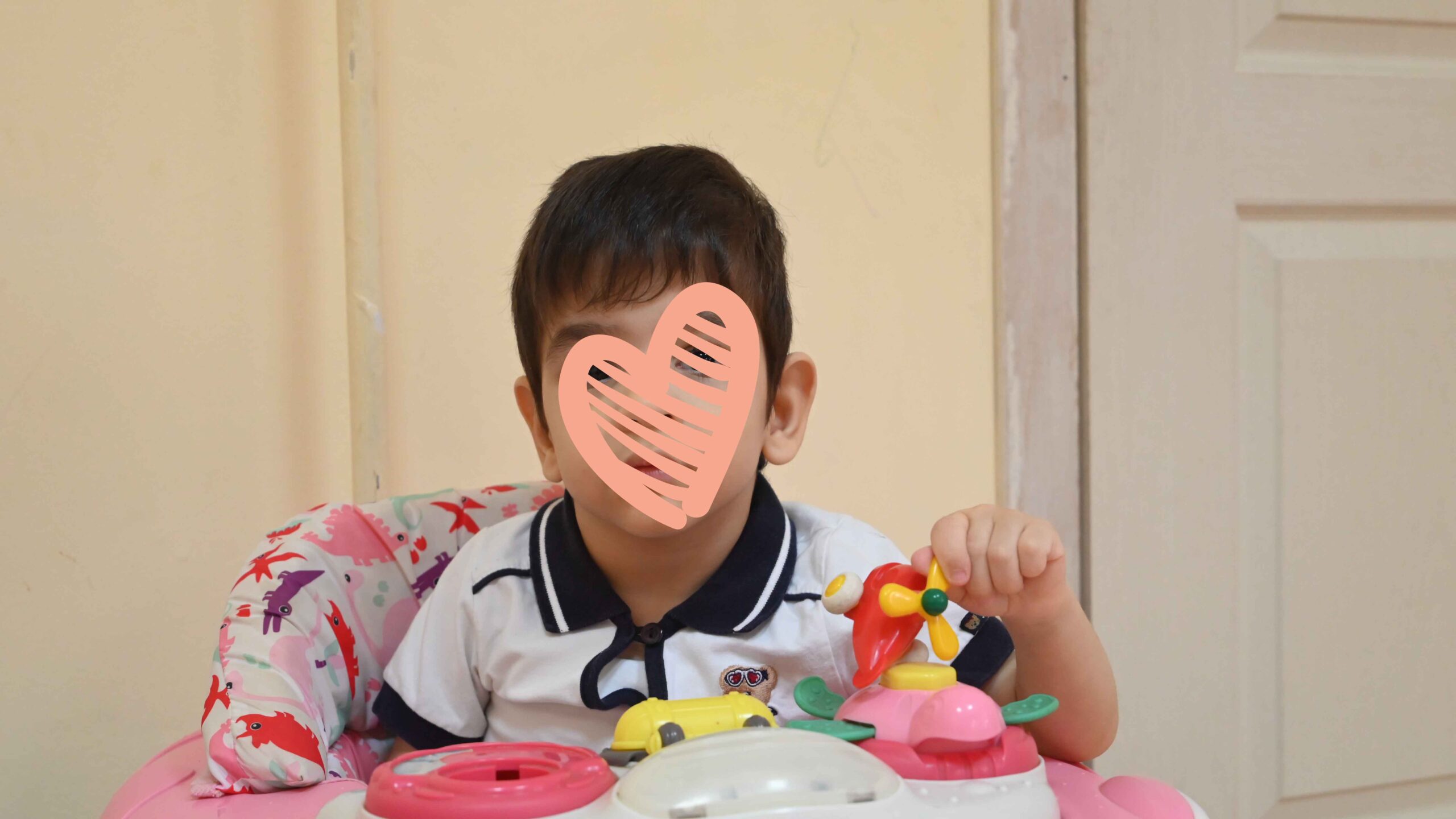 Little boy sits at a table and plays with colorful toys