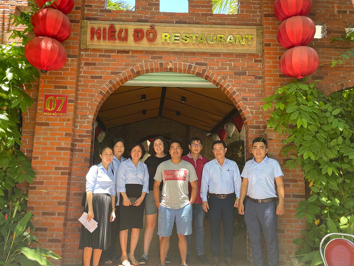 Vietnamese adoptee Chad Hassebrook and a group of people stands outside a restaurant in Vietnam