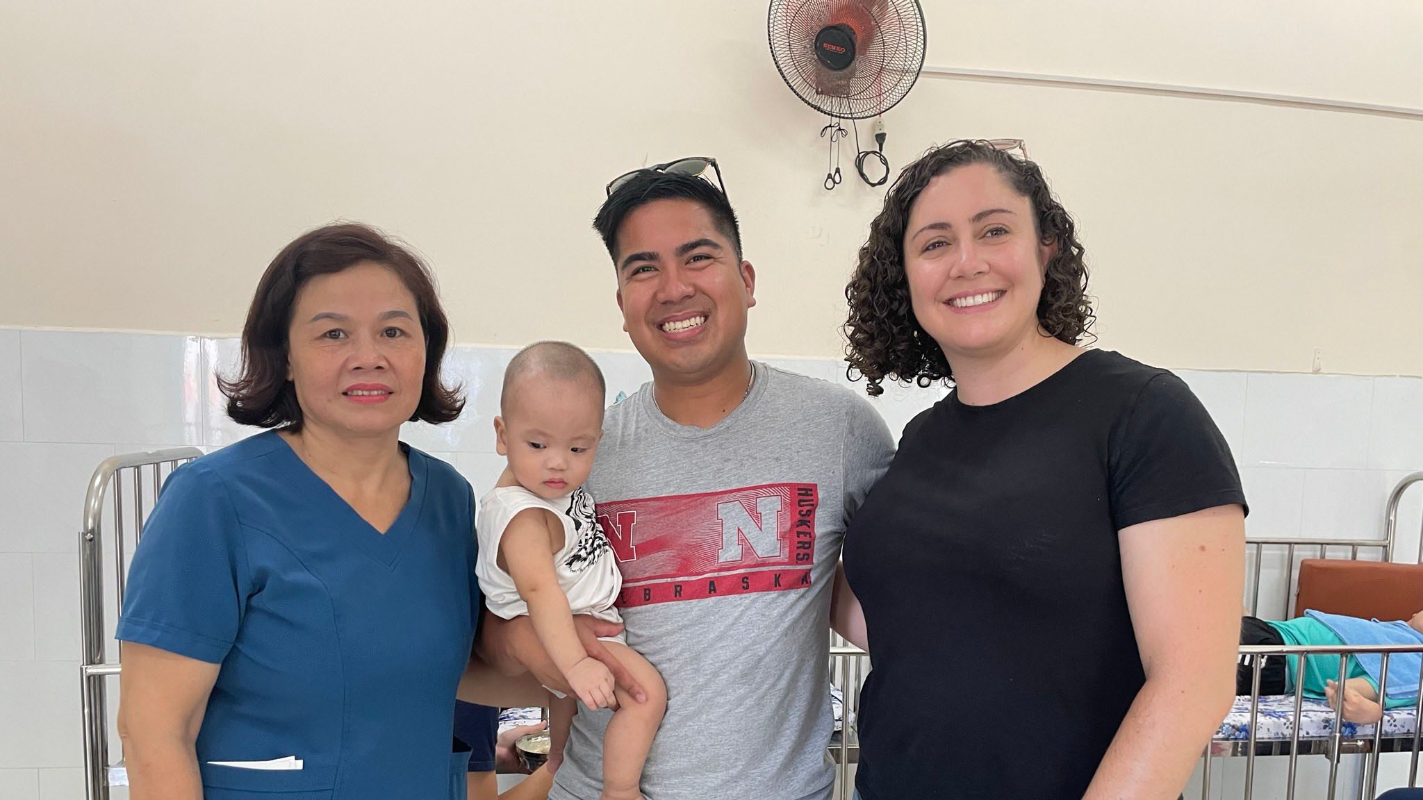 A couple holds a baby, next to a social worker in Vietnam