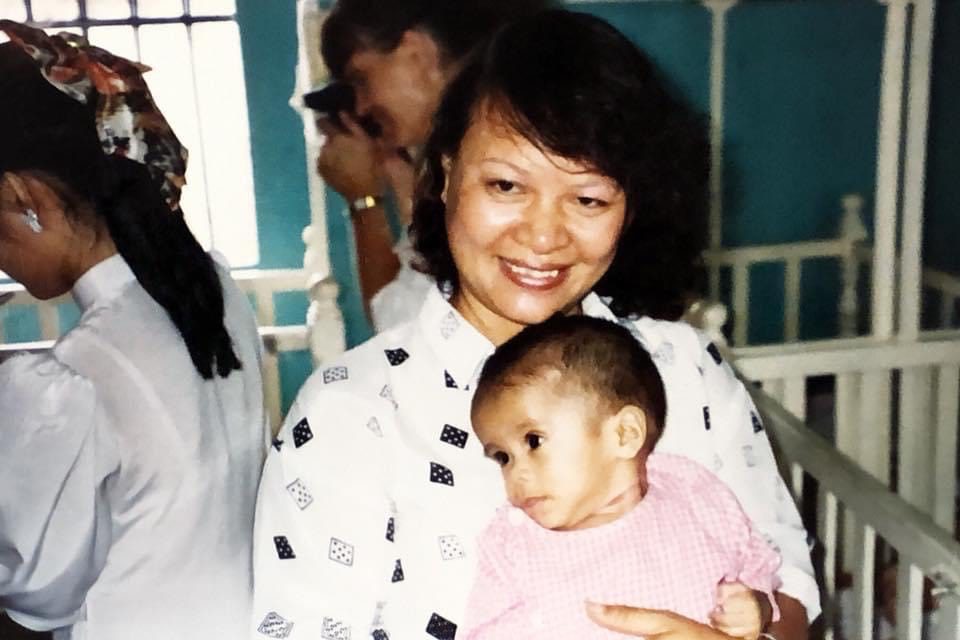 Vietnamese social worker holds small baby in a pink dress