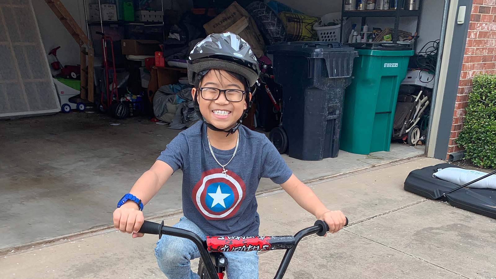 Boy smiles on his bike in family driveway