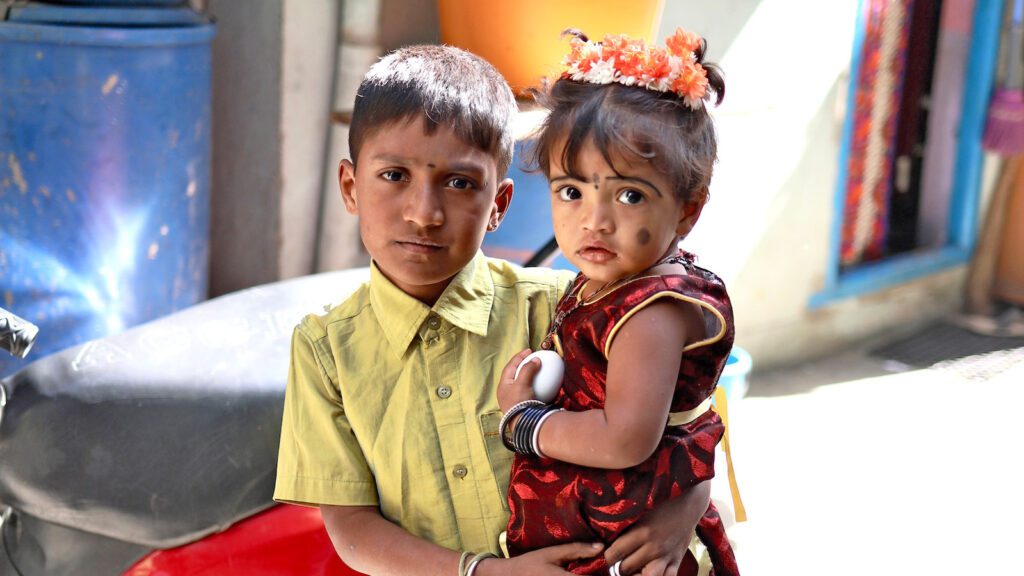 Big brother holding his letter sister in the streets of India