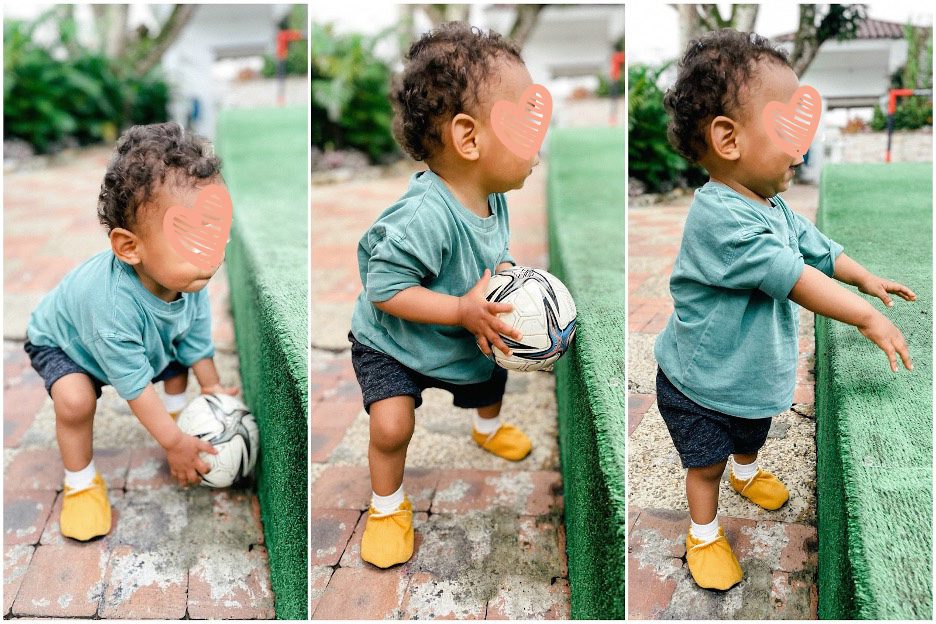 toddler stands up holding a soccer ball